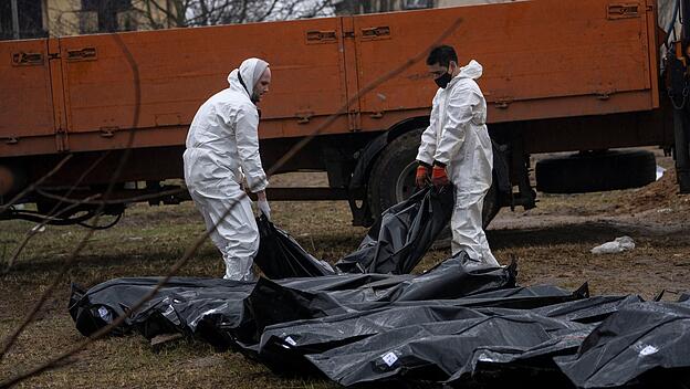 Butscha: Friedhofsarbeiter tragen die Leiche eines Mannes aus einem Massengrab