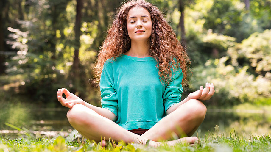 Beautiful girl practices yoga in the morning forest.