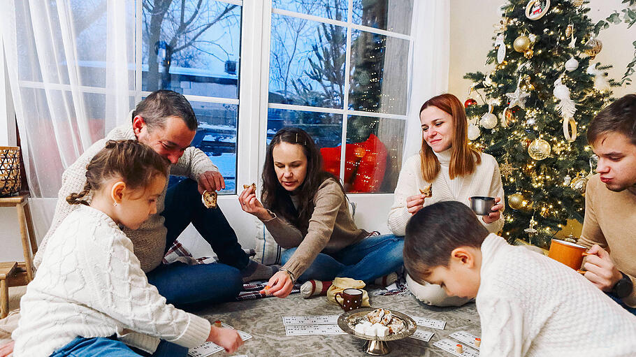 Family near Xmas tree playing lotto board game