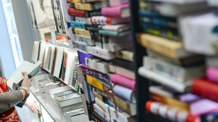 Eine Frau blättert auf einer Buchmesse in einem Buch