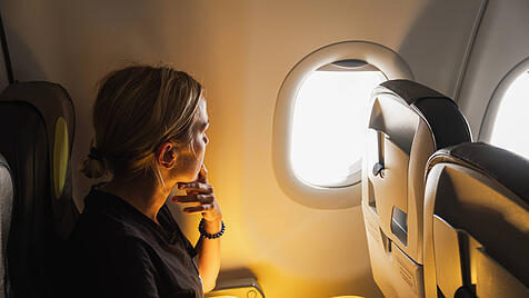 Happy Passagier Frau fliegt im Flugzeug. Mädchen sitzt im Flugzeug schauen aus dem Fenster gehen auf Reise Urlaub reisen. Traveling weiblich im Flugzeug genießen Flug. Traveling Mädchen.