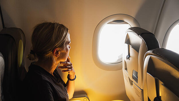 Happy Passagier Frau fliegt im Flugzeug. Mädchen sitzt im Flugzeug schauen aus dem Fenster gehen auf Reise Urlaub reisen. Traveling weiblich im Flugzeug genießen Flug. Traveling Mädchen.