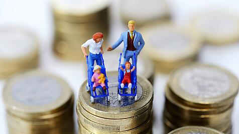 Miniaturfiguren einer Familie auf einem Münzstapel