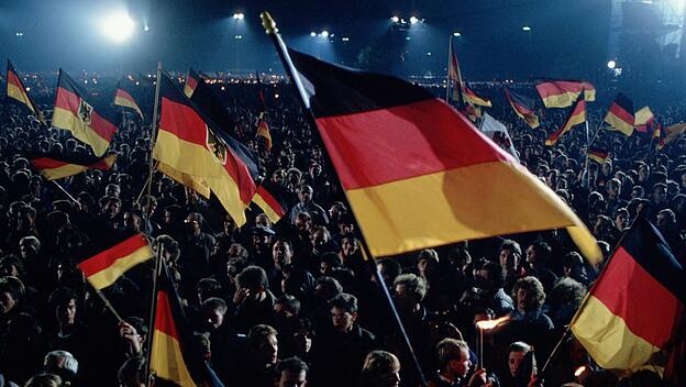 Menschen feiern die Deutsche Wiedervereinigung dabei schwenken sie deutsche Flaggen und Fahnen Berl