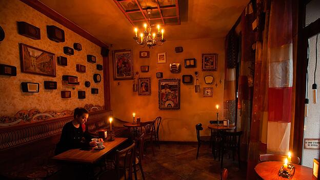 Eine Frau sitzt in einem mit Kerzen beleuchteten Restaurant, während eines Stromausfalles