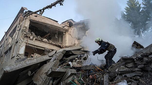 Rettungsarbeiter säubert die Trümmer einer zerstörten Schule in Charkiw