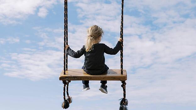 Kleines M&auml;dchen schaukelt auf einer Seilschaukel am Meeresufer
