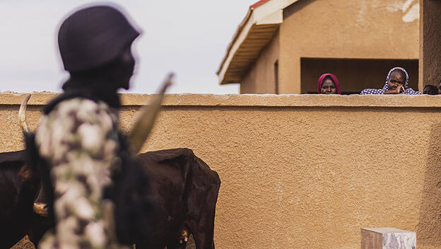Zwei Frauen zeichnen sich hinter einer Mauer ab, aufgenommen in dem Dorf Ngarannam