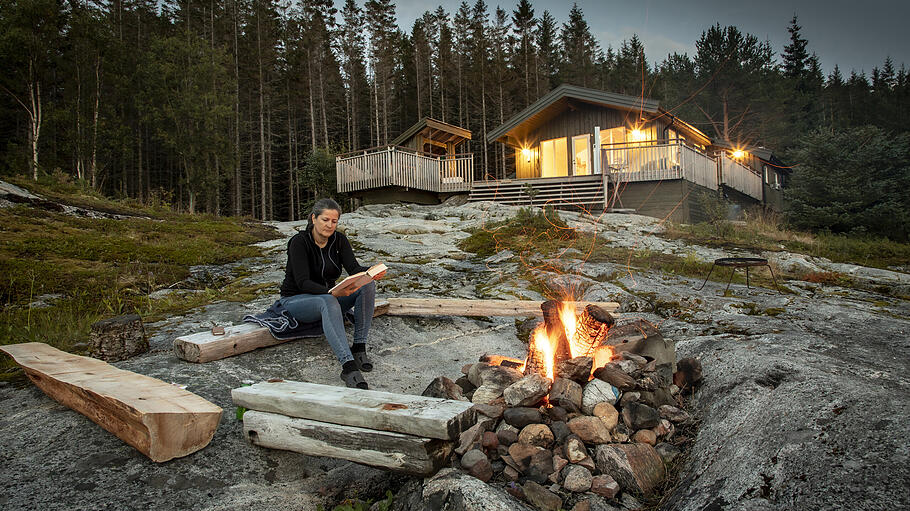 woman reading beside campfire in norway