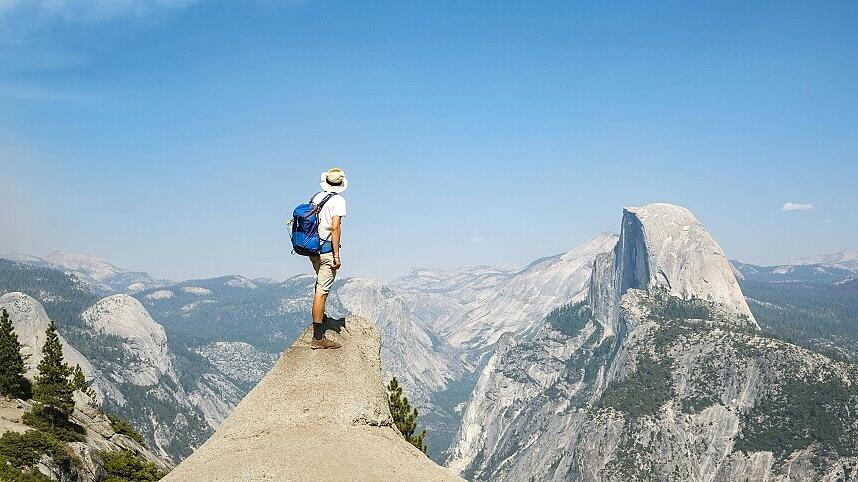 Junger Mann steht auf Felsvorsprung und blickt auf den Half Dome Ausblick vom Glacier Point Yosemi