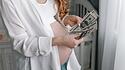 Frau mit Babybauch und Dollarscheinen