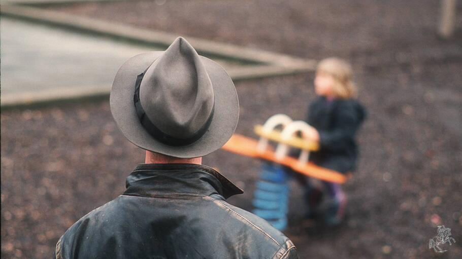 Mann beobachtet ein Kind auf dem Spielplatz