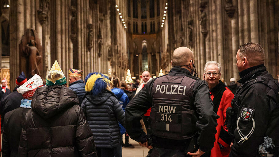 Polizisten stehen im Dom neben Karnevalisten.