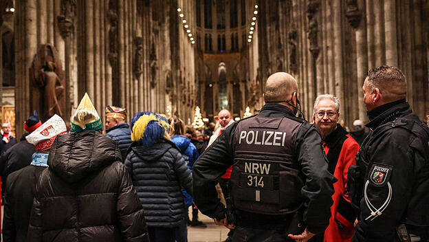 Polizisten stehen im Dom neben Karnevalisten.