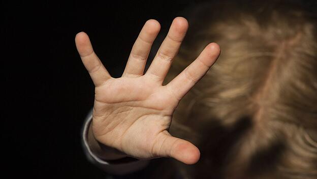 Kind wehrt sich mit ausgestreckten Armen.