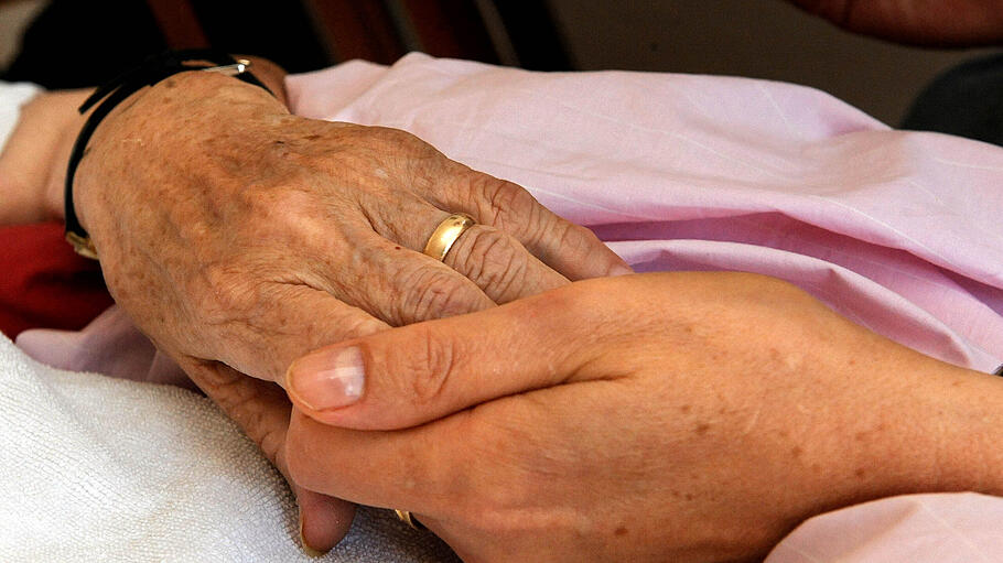 Eine Schwester hält im Hospiz die Hand einer sterbenden Bewohnerin.
