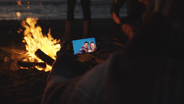 RECORD DATE NOT STATED Boy Shows Girl A Picture On His Phone beside campfire on beach *** Junge zeigt M�del einer Bild a