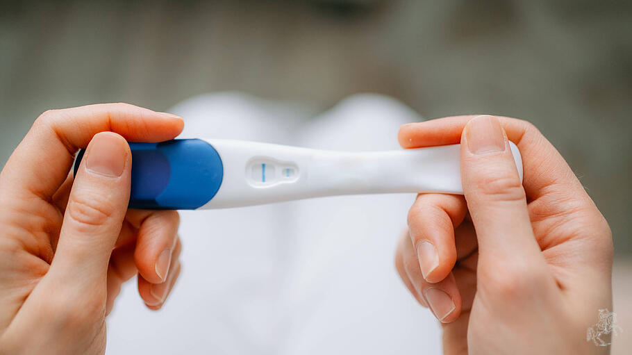 Frau mit einem Schwangerschaftstest, der ein negatives Ergebnis anzeigt.