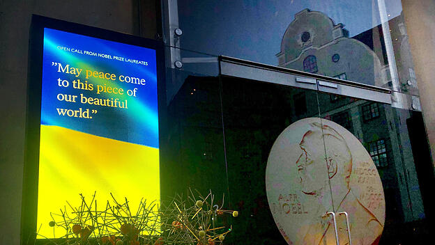 Auf einem Bildschirm vor dem Nobelpreismuseum in Stockholm ist eine Ukraine-Flagge zu sehen