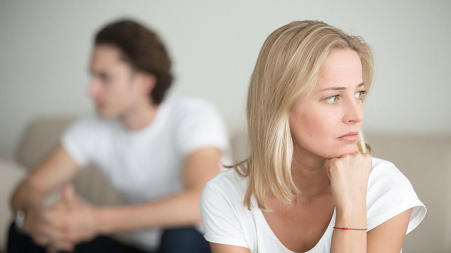 Sad woman thinking over a problem, man sitting aside