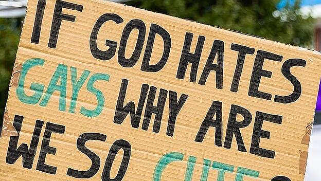 Homosexuelle Demonstranten provozieren mit der Behauptung, die Kirche lehre ihre sexuelle Präferenz zu „hassen“.
