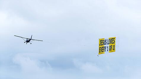 Christliche Werbekampagne: Flugzeug, das ein Transparent mit einer religiösen Botschaft schleppt.