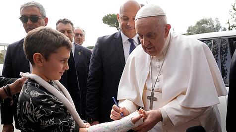 Papst Franziskus unterschreibt den Gipsabdruck eines Kindes