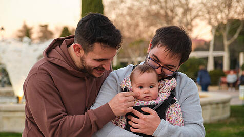 Homosexual happy couple playing with their baby in a baby carrier. Madrid, Community of Madrid, Spain CR_CRVI240216-1352