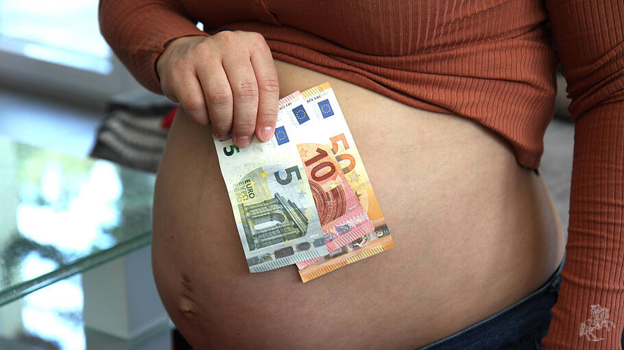 Schwangere Frau mit Babybauch und Geldscheinen