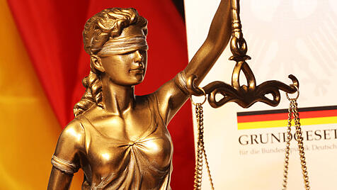 Nahaufnahme einer Justitia vor dem deutschen Grundgesetzbuch *** Close-up of a Justitia in front of the German Basic Co