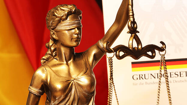 Nahaufnahme einer Justitia vor dem deutschen Grundgesetzbuch *** Close-up of a Justitia in front of the German Basic Co