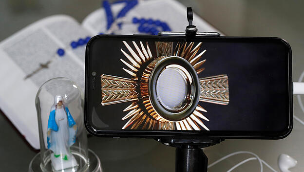 Eucharistie in einer Monstranz auf einem Handybildschirm