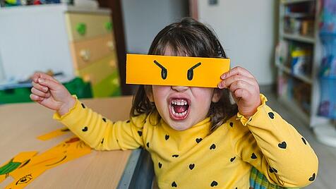 Girl making angry face while holding emoticon at home model released Symbolfoto property released MGIF01068