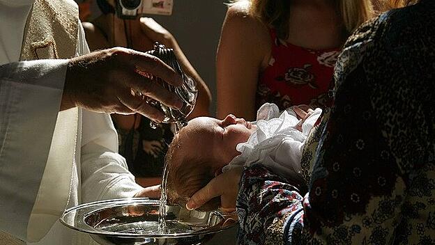 Taufe - Pfarrer begießt den Kopf des  Kindes mit Weihwasser