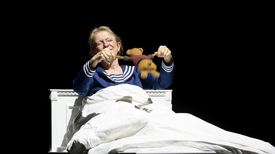 Dagmar Manzel, Schauspielerin in einem Bett auf dunkler Bühne