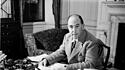 C. S. Lewis im Tweed-Anzug an seinem Schreibtisch.