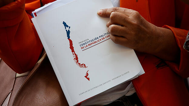 Ein Demonstrant hält ein Exemplar des neuen Verfassungsentwurfs auf einer Kundgebung in Chile.
