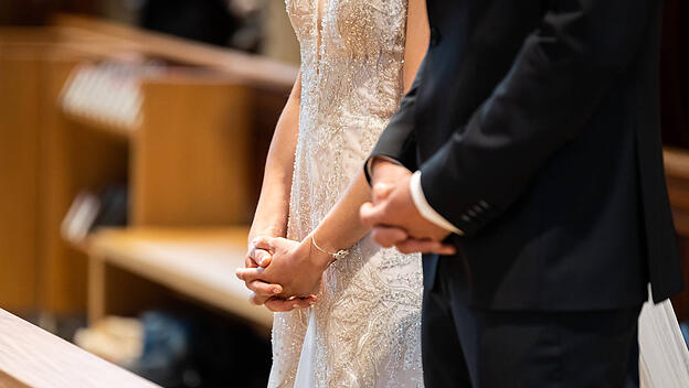 Ein Brautpaar faltet während ihrer Trauung in einer katholischen Kirche die Hände. Rottweil Baden-Württemberg Deutschla