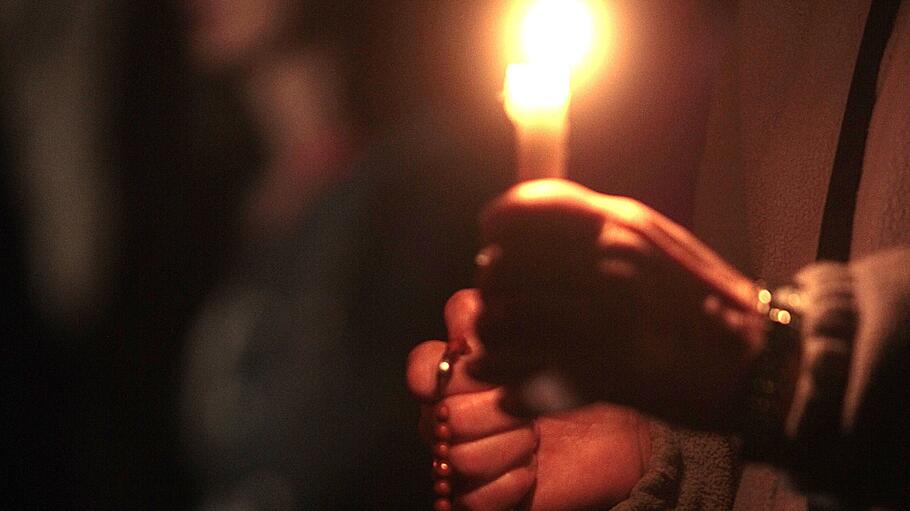 Eine Hand hält eine brennende Kerze