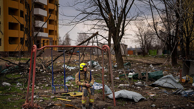 Feuerwehrmann sitzt auf einer Schaukel neben einem Gebäude