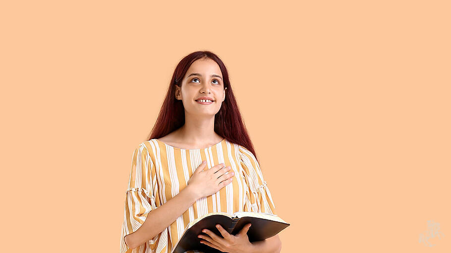 Teenage girl with Holy Bible on beige background