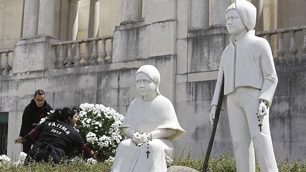 Fatima: Helfer schmücken mit Blumengebinden die Wiese mit den Statuen der beiden Seherkinder