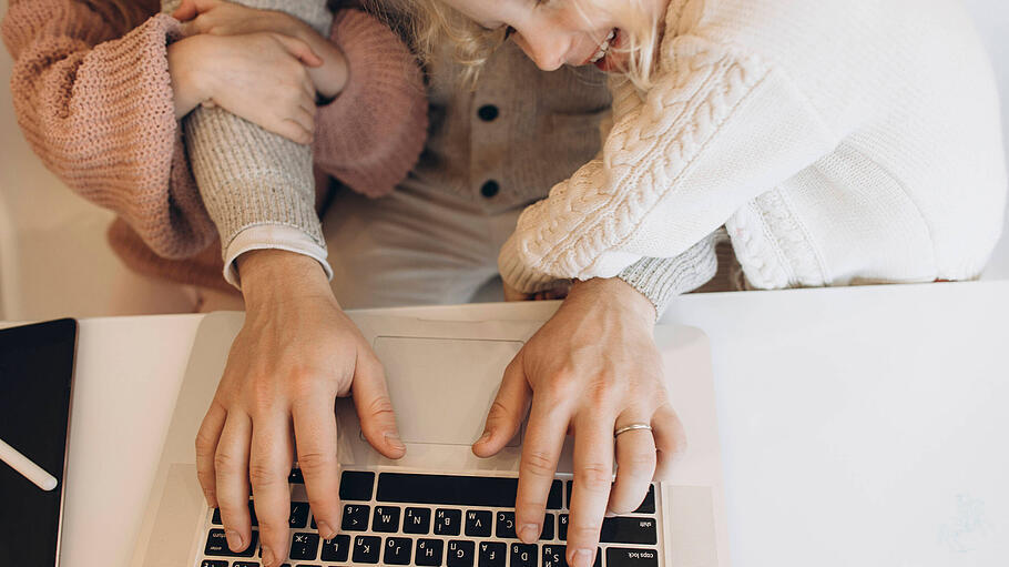 Ein Vater, umringt von Kindern, tippt auf einem Laptop