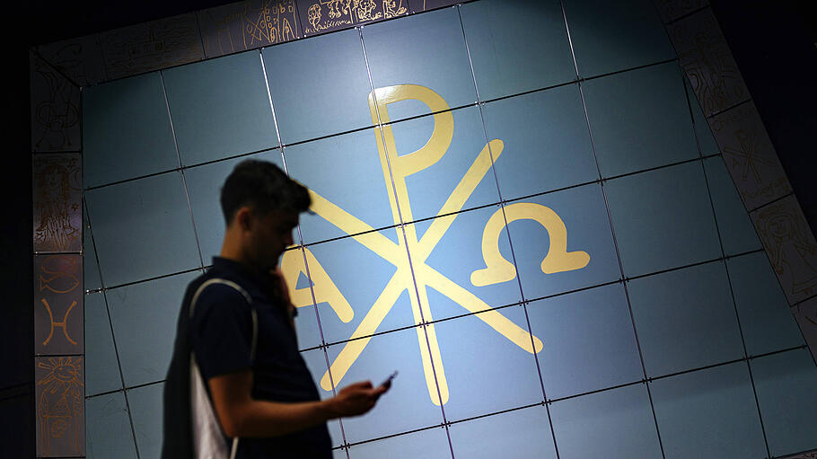 Ein Fahrgast posiert vor den Symbolen des Christentums im Hauptbahnhof.