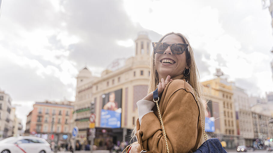 A shallow focus of a young Hispanic woman with sunglasses holding shopping