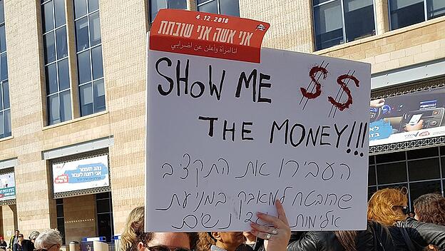 "Ich bin eine Frau und ich streike" steht auf Hebräisch auf dem roten Aufkleber.