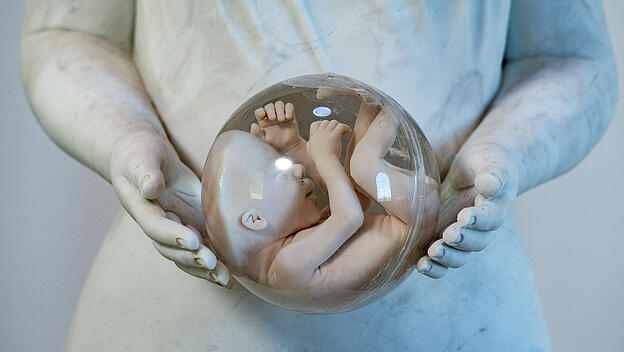 Eine Marienstatue hält eine Glaskugel mit dem Bild eines ungeborenen Kindes in den Händen.