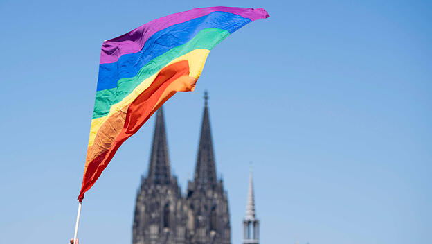 LGBTQ-Flagge vor einer Kirche.