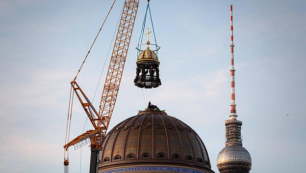 Der Kuppel des Humboldt-Forums in Berlin wird das Kreuz aufgesetzt.