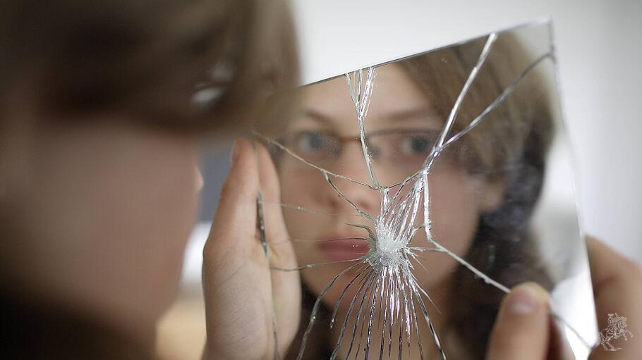 Ein Mädchen vor einem zerbrochenen Spiegel